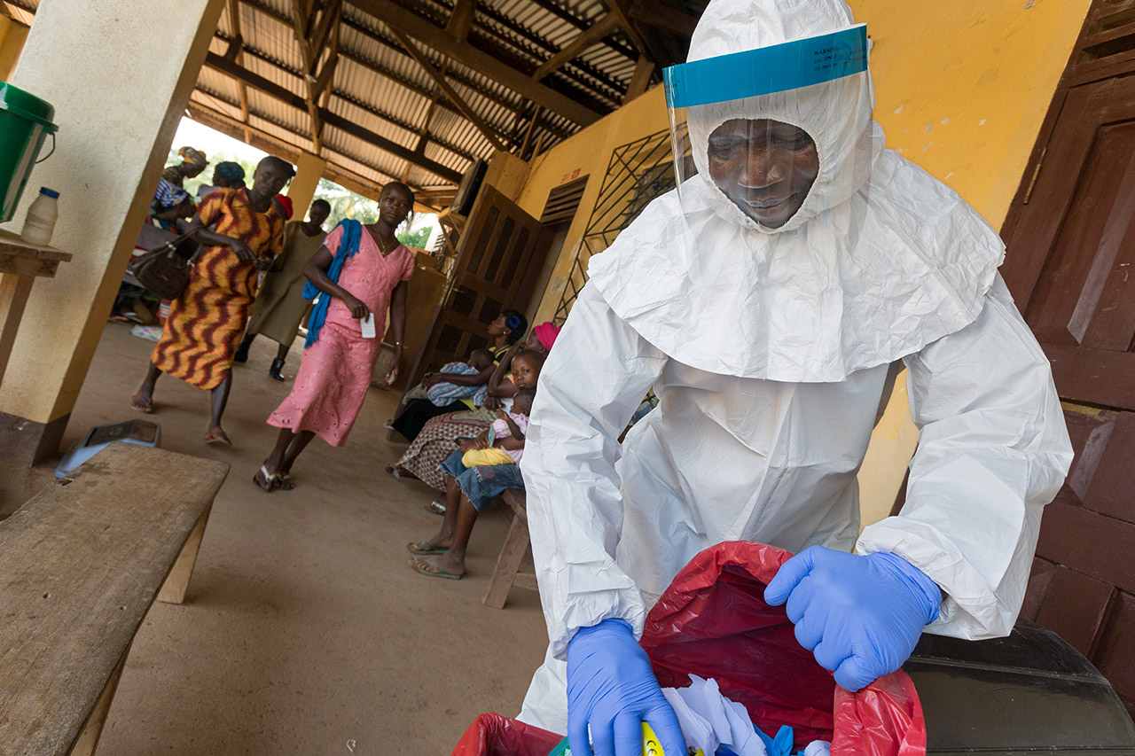 Liberia während der Ebola-Seuche: Ein Krankenhaus-Mitarbeiter entsorgt in einem Schutzanzug Krankenhausabfälle. Photo: Christoph Püschner/Diakonie Katastrophenhilfe